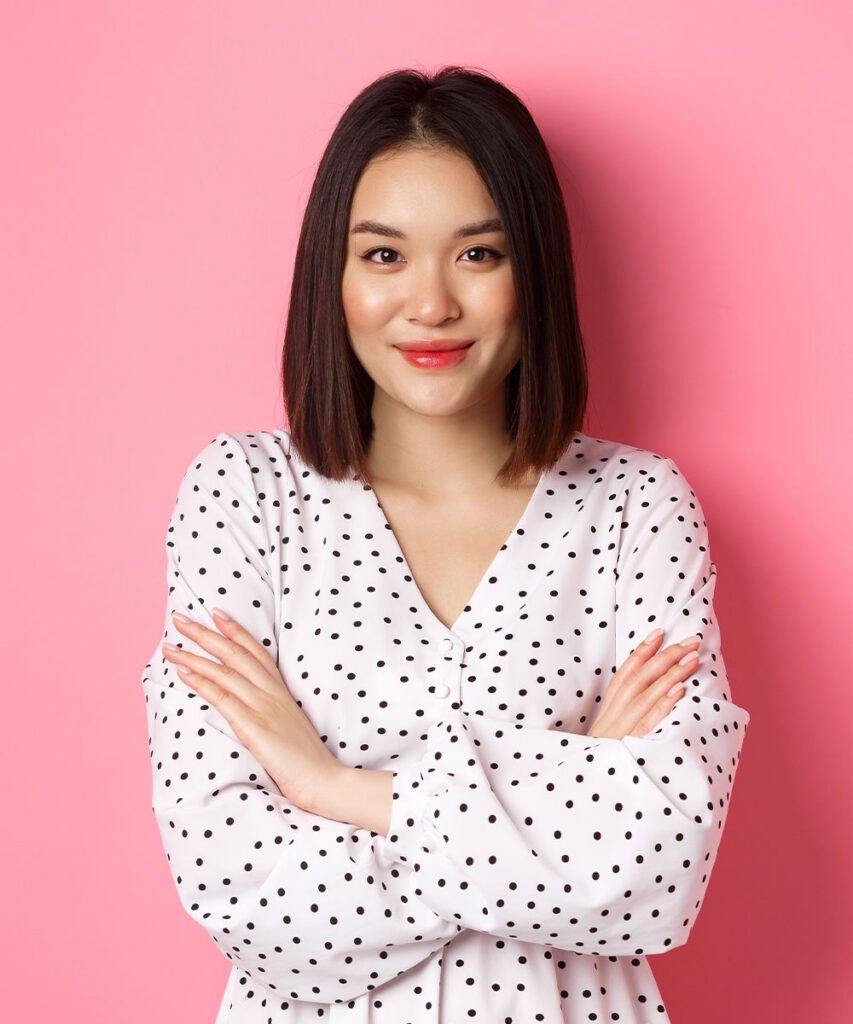 a woman with black hair and white shirt with black dots on it