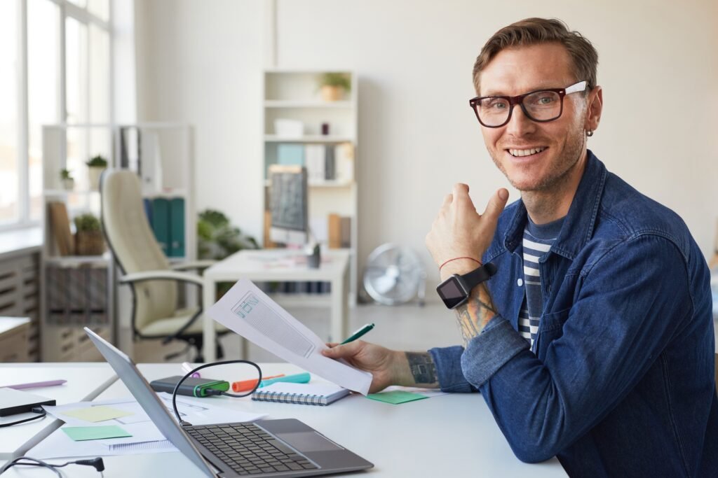 a man sitting at a desk with a laptop and a paper