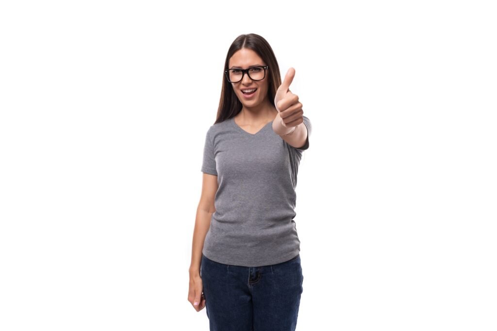 a woman wearing glasses and a grey shirt giving a thumbs up