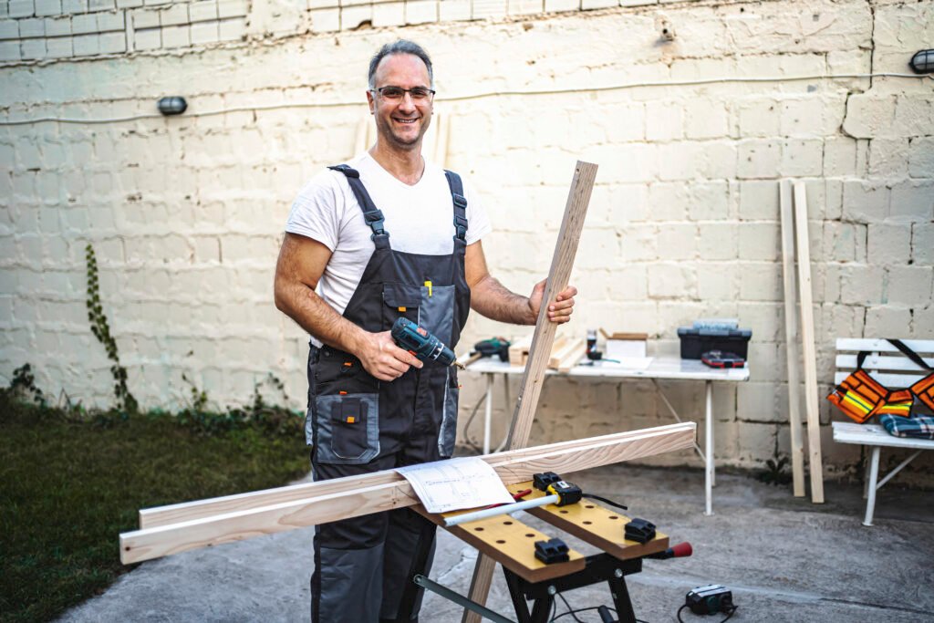 Mature male carpenter working with electrical screwdriver on a w